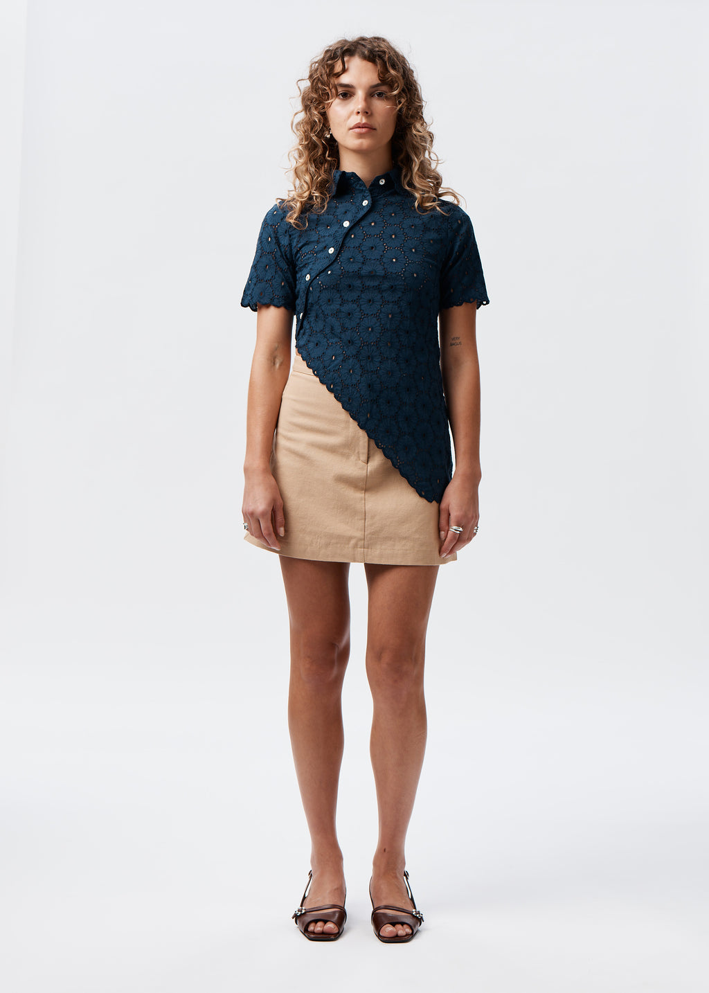 Say the Label Daisy Asymmetric Top in navy with daisy embroidery, worn with a beige skirt
