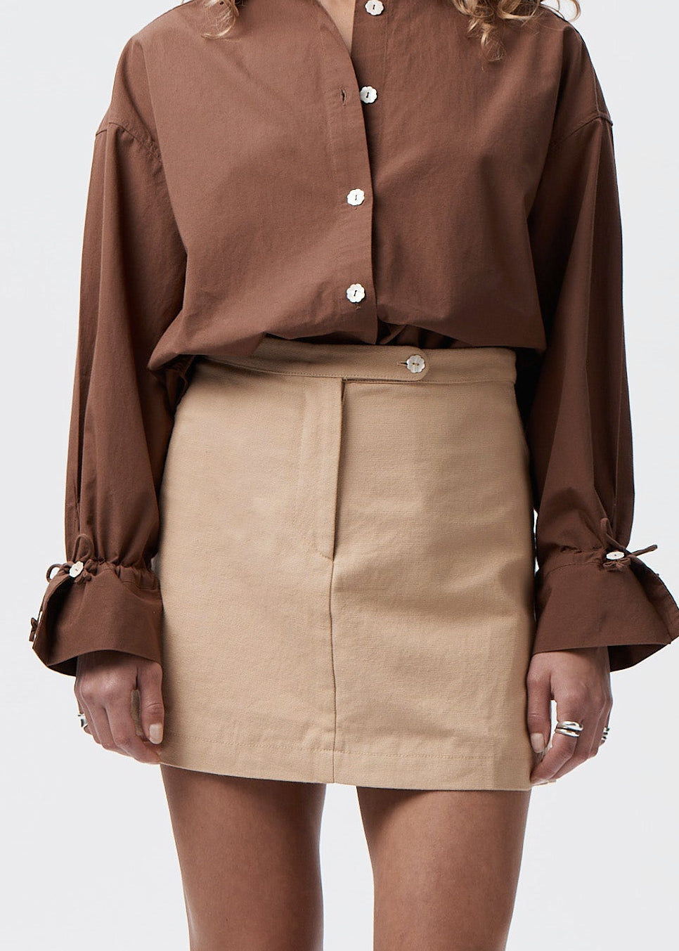 Say the Label Wave Mini Skirt in latte worn with a brown blouse, front view